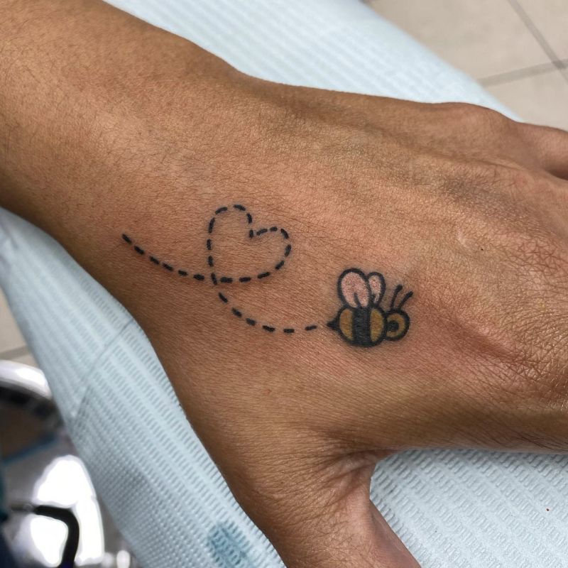 Tatuagem na mão na forma de um Bumblebee voador com um coração