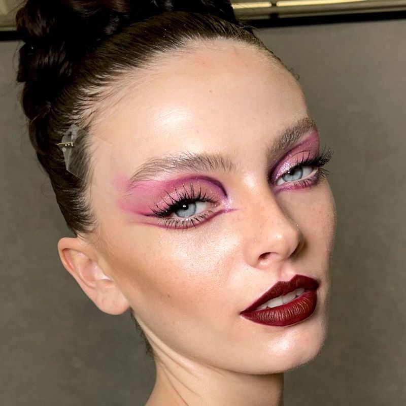 Modelo com maquiagem abstrata e rosa-violeta e batom de Borgonha