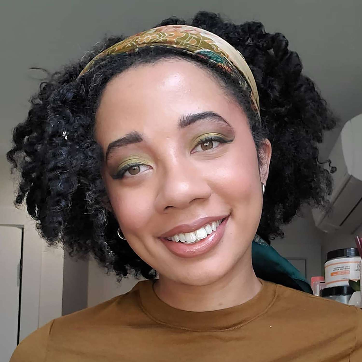 O fechament o-up do editor de beleza Byrdie Eden Stewart em maquiagem verde e marrom com matty leite