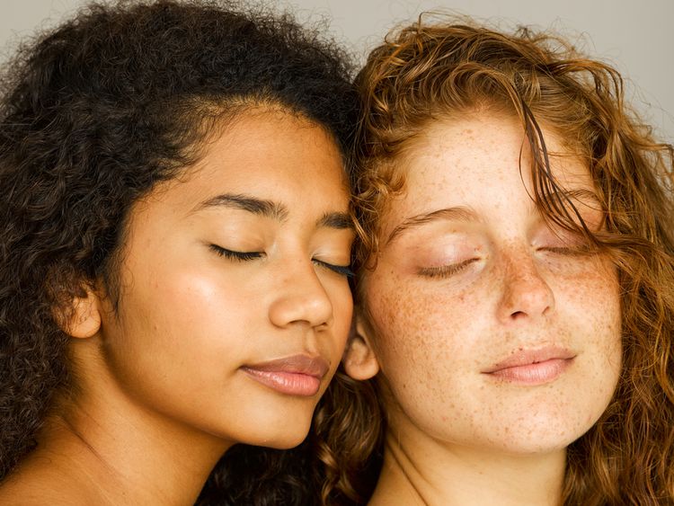Duas mulheres com pele brilhante e olhos fechados