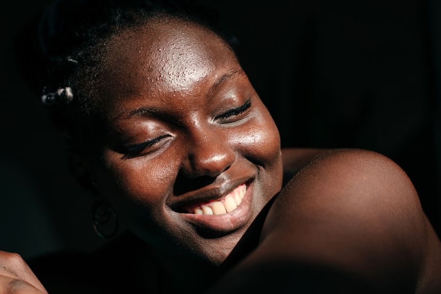 Uma pessoa sorridente com pele luminosa em um fundo preto