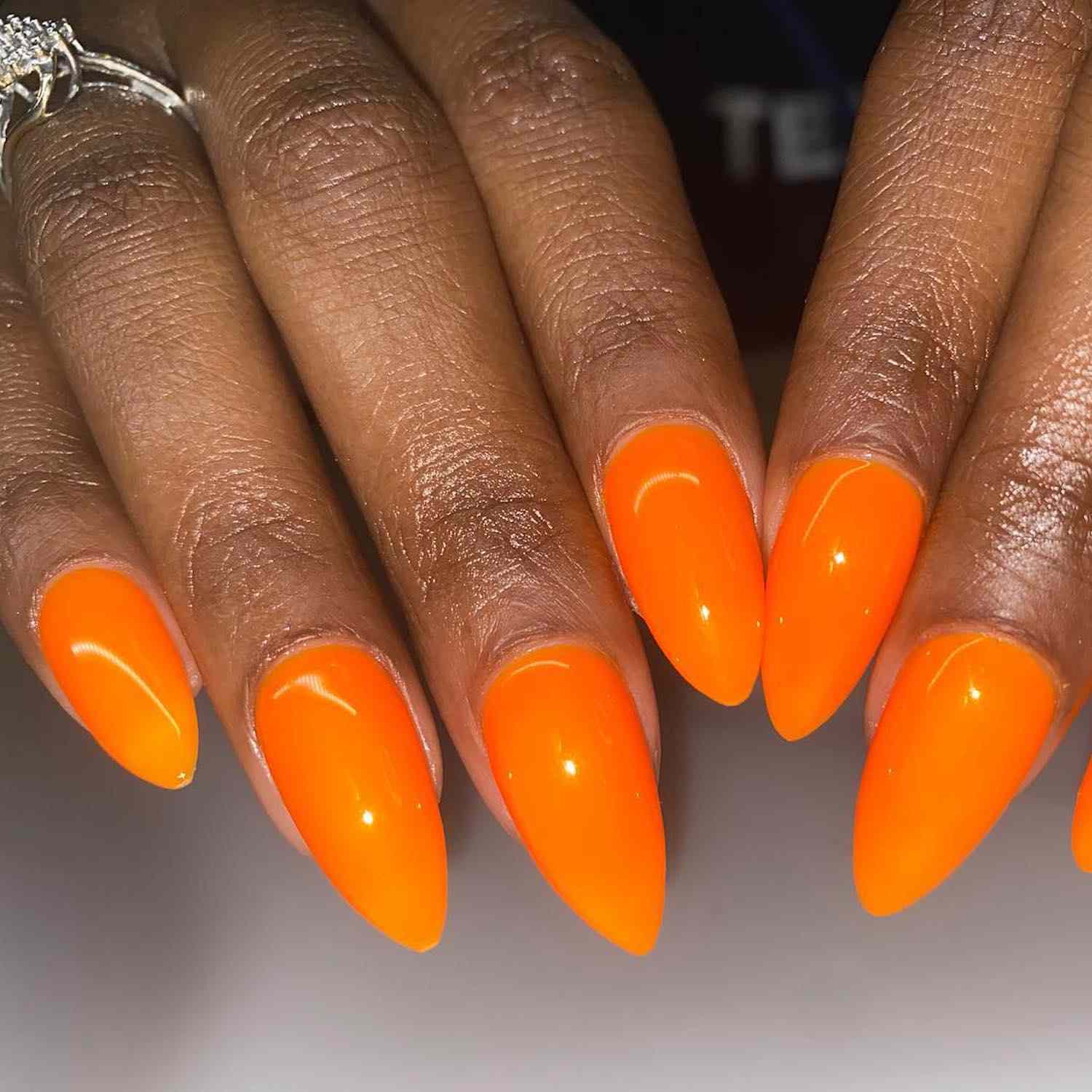 Manicure laranja brilhante em uma forma alongada em forma de amêndoa