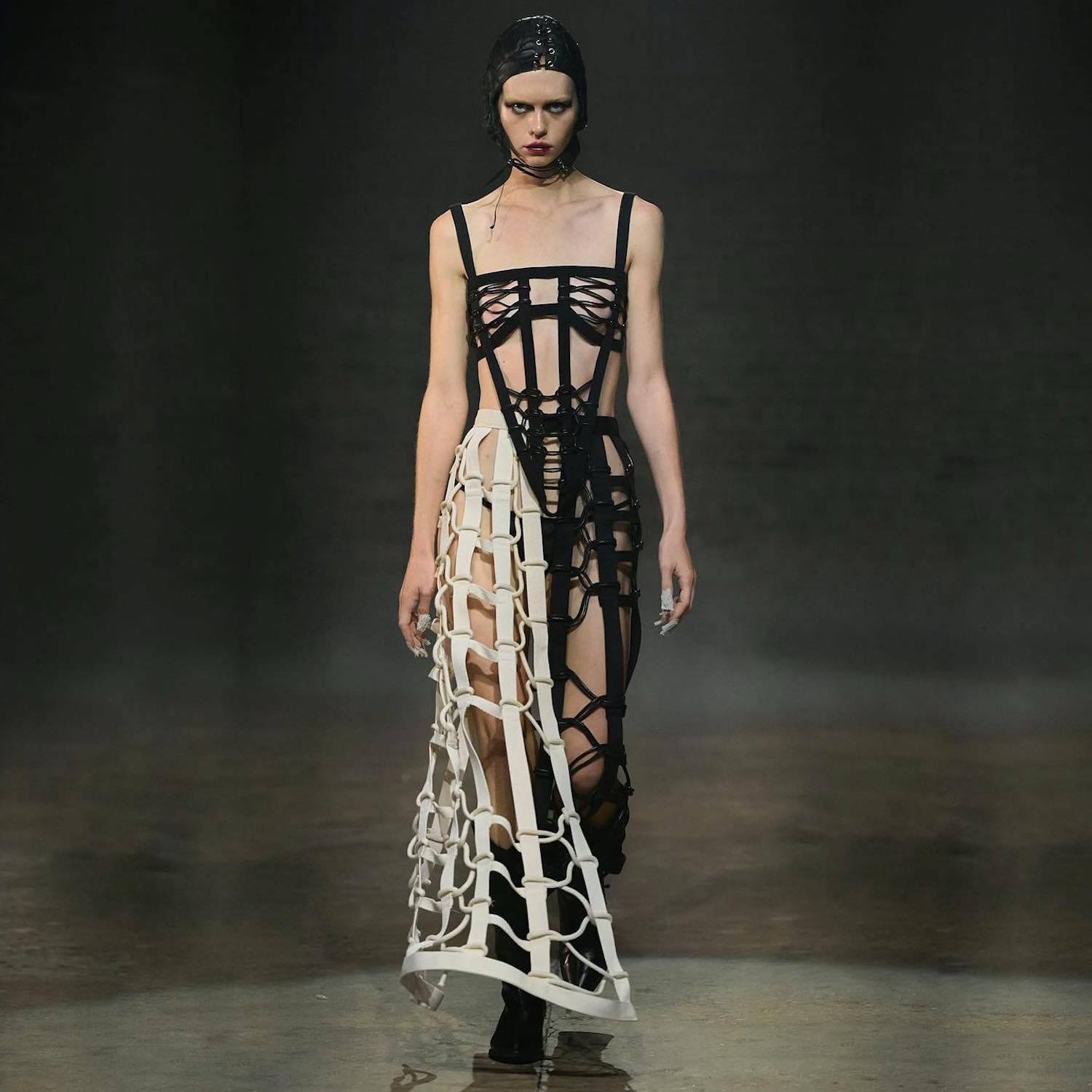 O modelo passa pela passarela em um vestido de Bando em preto e branco de Elena Velez