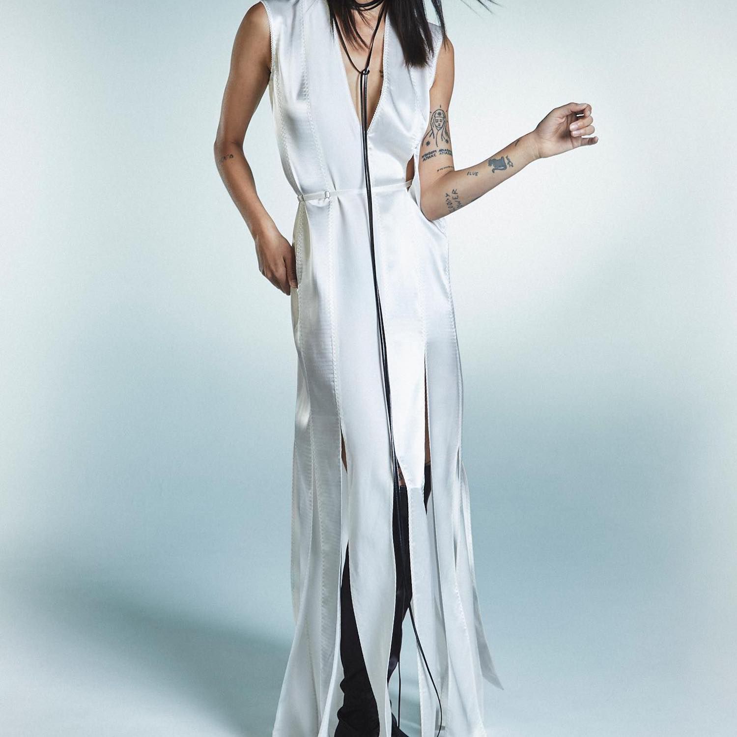 Um modelo em um vestido de seda branco com uma saia serpentina e um colar de multicamadas preto de um cordão