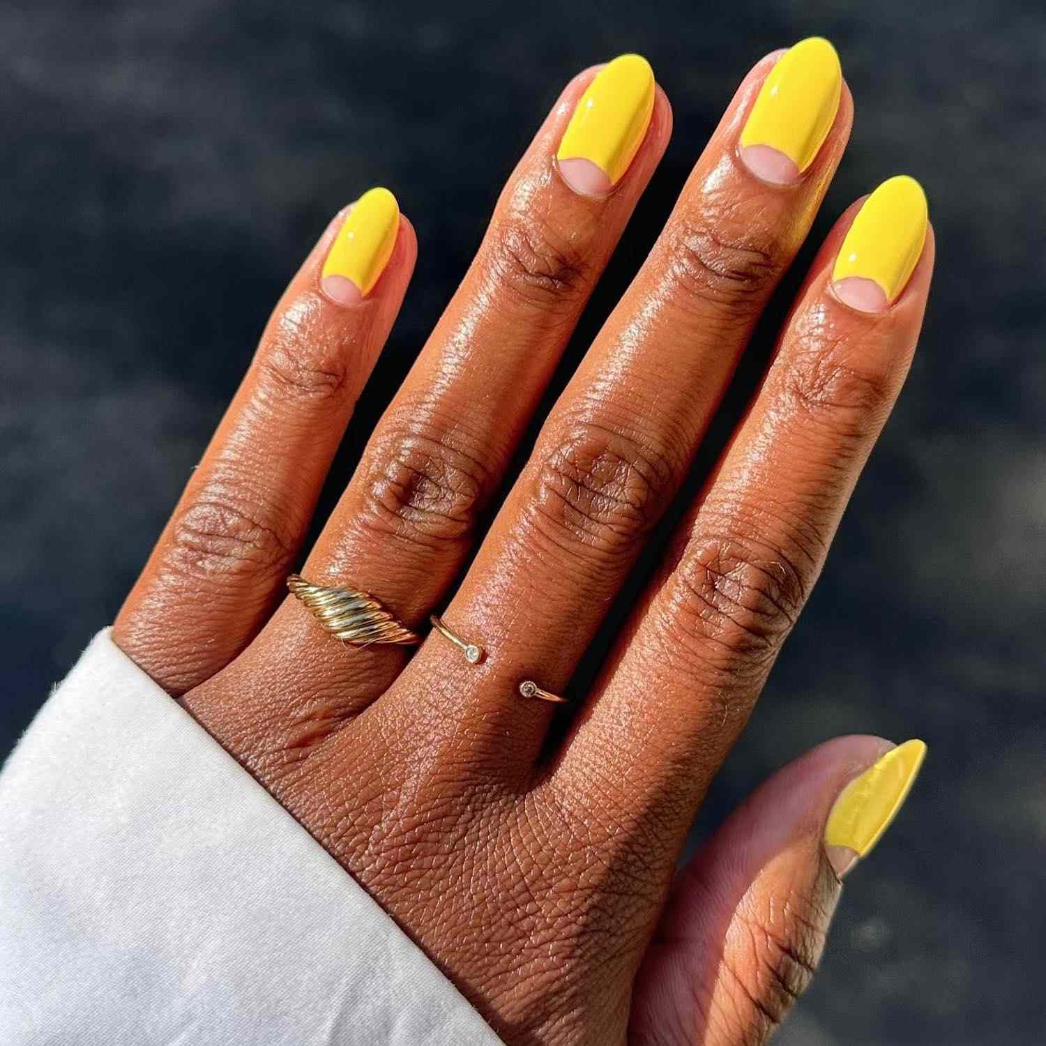 Manicure amarela brilhante com um design crescente de uma cutícula com espaço negativo