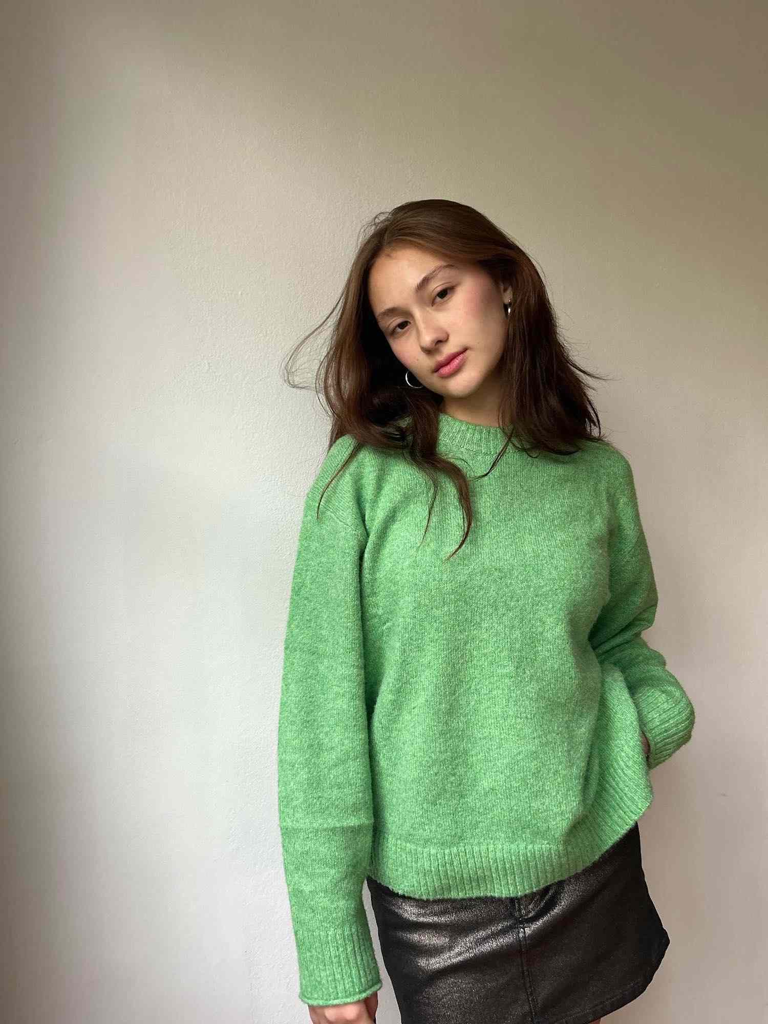 Lola Tung em um suéter verde, uma minissaia de couro e Silver-Sobs.