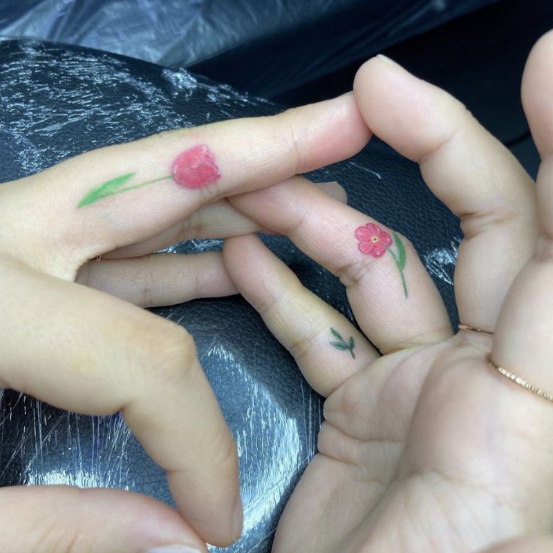Tatuagens nos dedos na forma de flores vermelhas e verdes