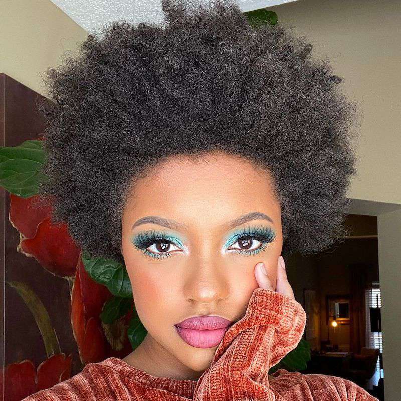 Mulher com penteado afro e maquiagem brilhante