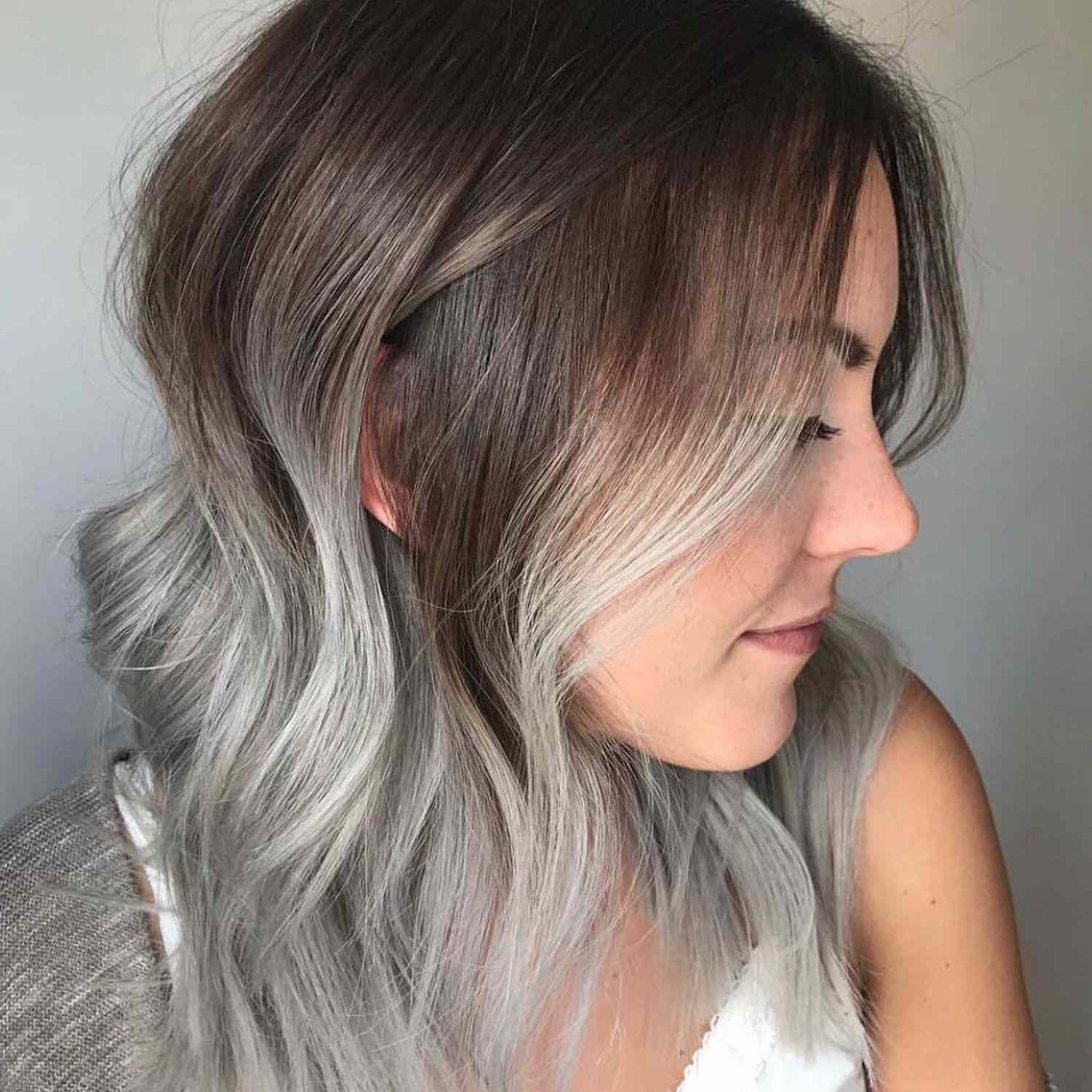 A vista lateral do cabelo com cabana de prata defumada e raízes brunéias