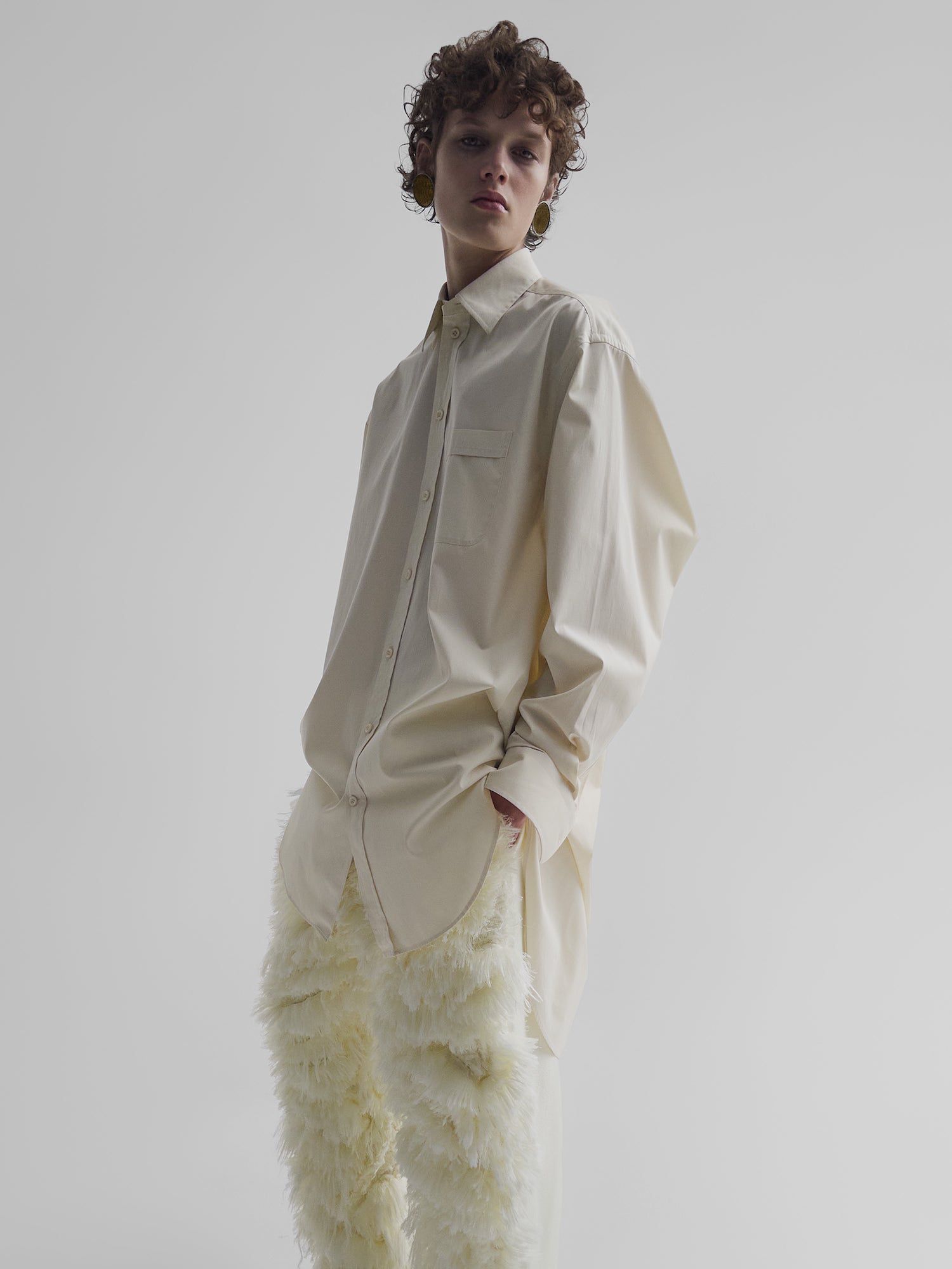 Modelo em uma camisa branca em botões e calças texturizadas de tamanhos grandes de Phoebe Philo