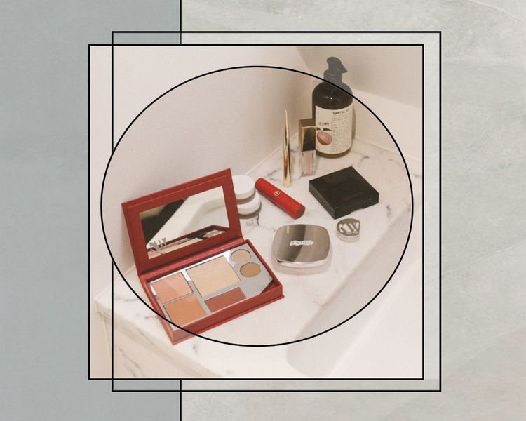 Diversas paletas e produtos de maquiagem em bancada de mármore branco no banheiro
