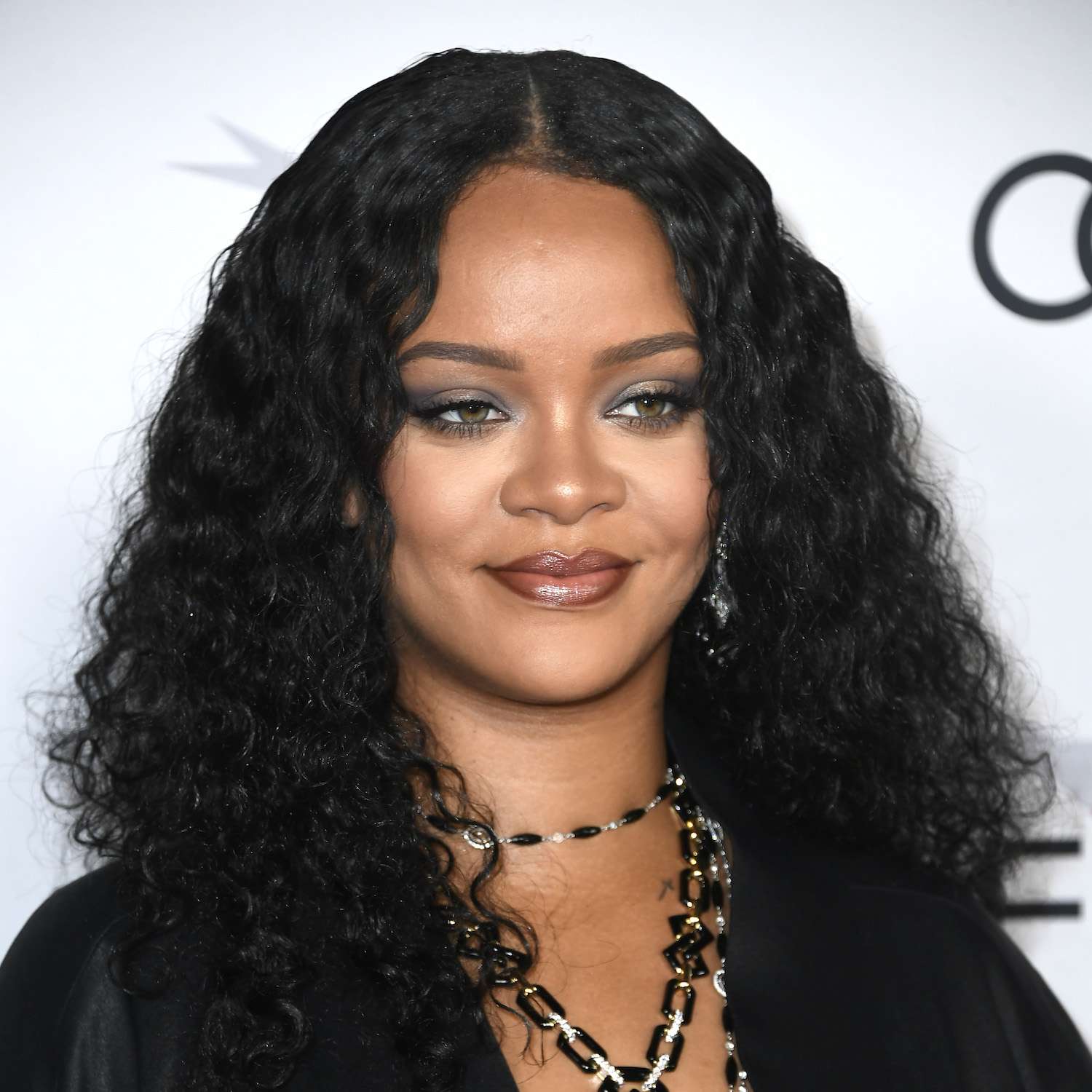 Rihanna usa um penteado com cabelos longos e encaracolados e um fino enquadramento
