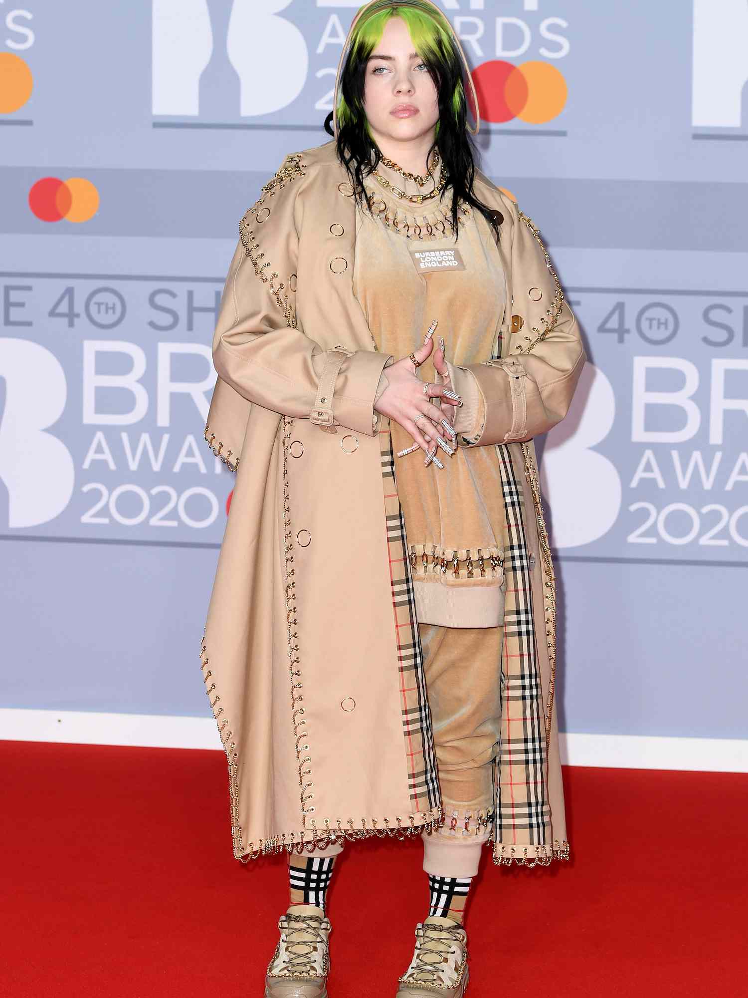 Billie Eilish usa sobretudo Burberry, shorts, meias, tênis e boné no Brit Awards 2020