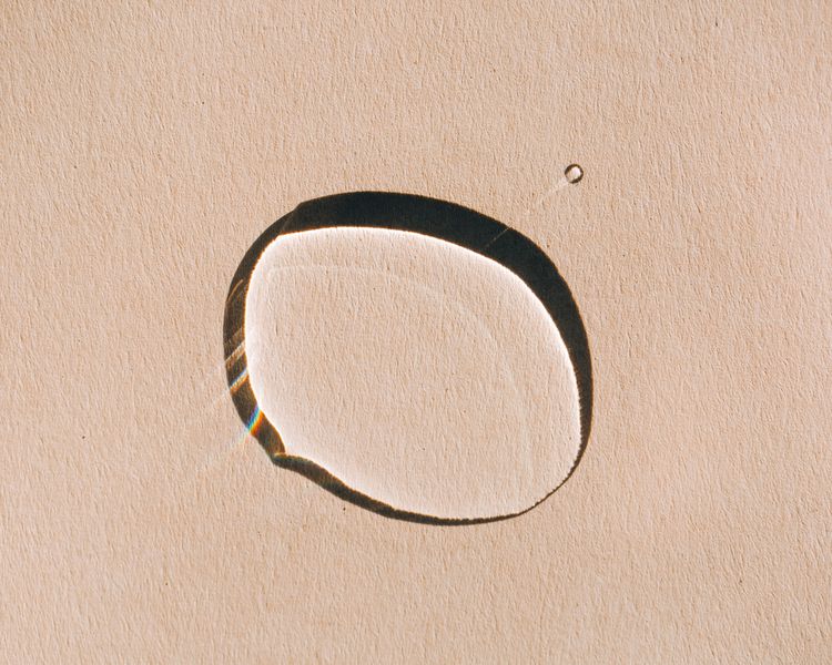 Uma gota de óleo para cuidados com a pele em um fundo bronzeado