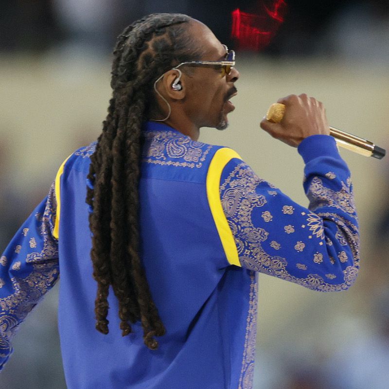 Snoop Dogg usa seus dreadlocks característicos e uma camisa azul estampada