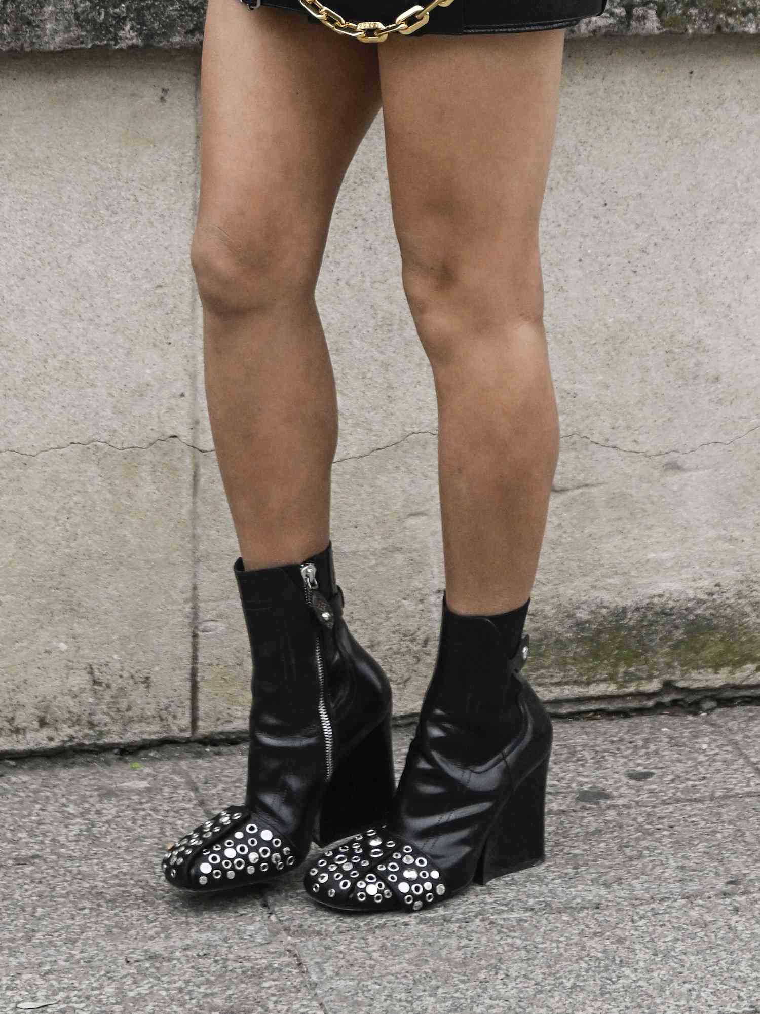 Close de Aimee Song usando botas de couro pretas com pontas e zíperes