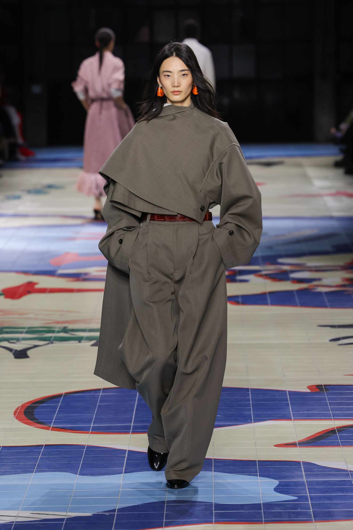 : O modelo está andando ao longo da passarela no show de Bottega Veneta em uma roupa completamente cinza