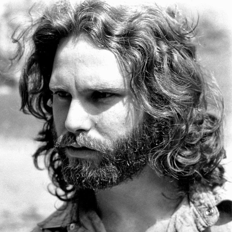 Jim Morrison com seu cabelo e barba ondulados característicos