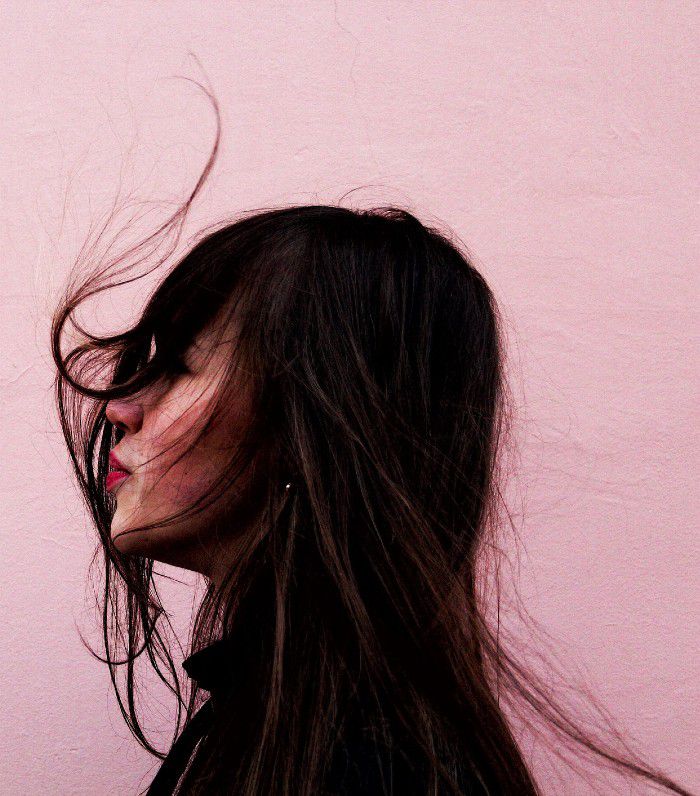 Close de uma jovem com o cabelo penteado contra uma parede