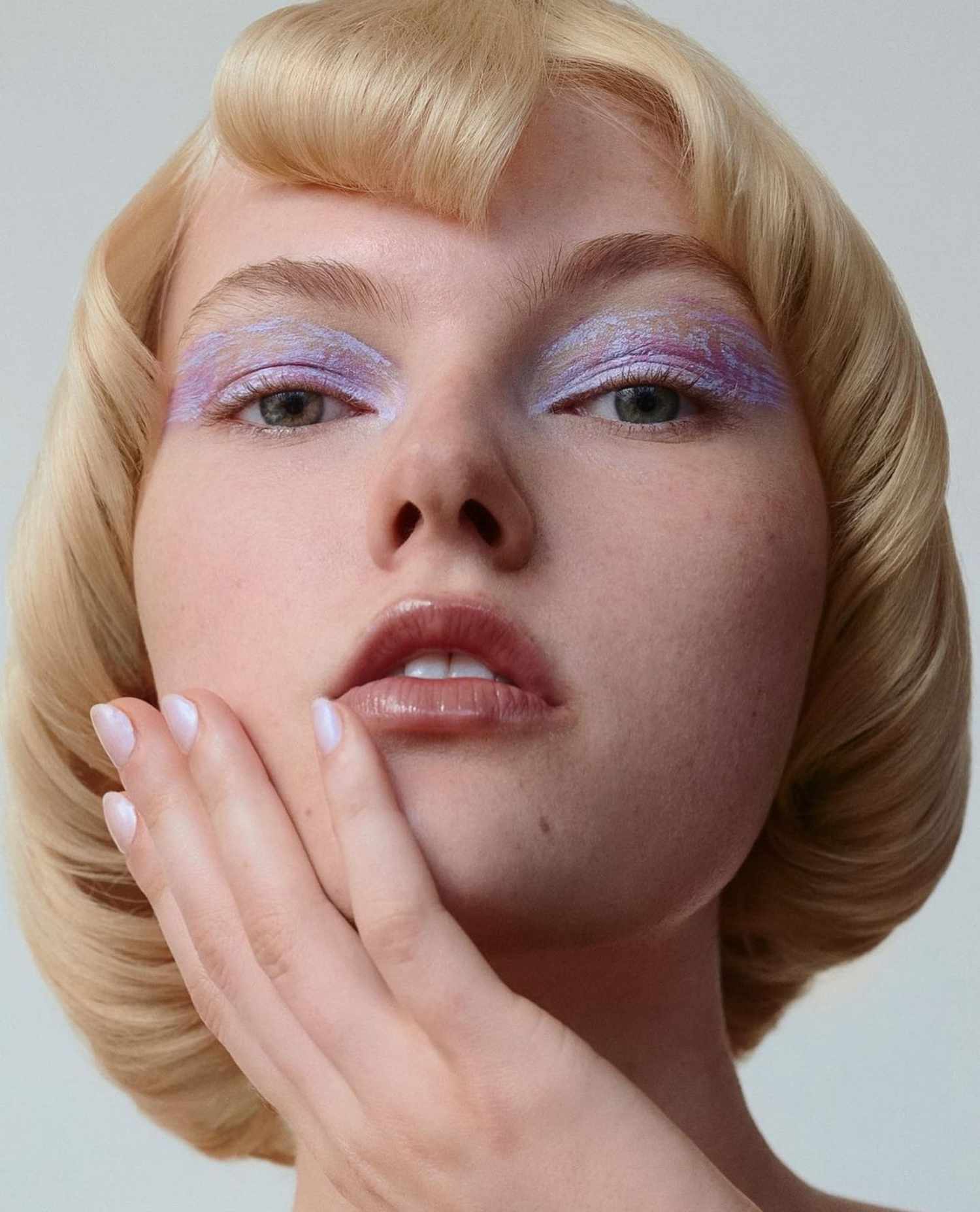 Foto aproximada de uma modelo com maquiagem lilás aplicada nas pálpebras