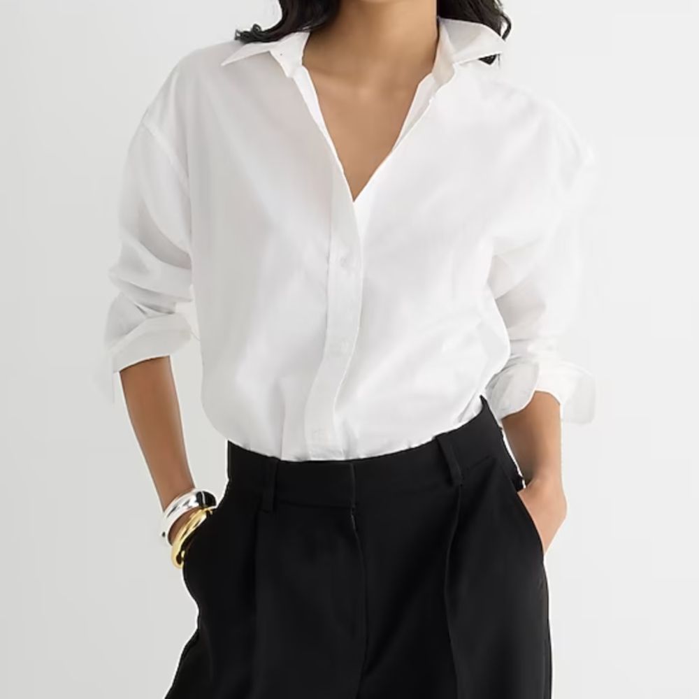 Modelo em uma camisa branca em botões dobrados em calças pretas, um aumento