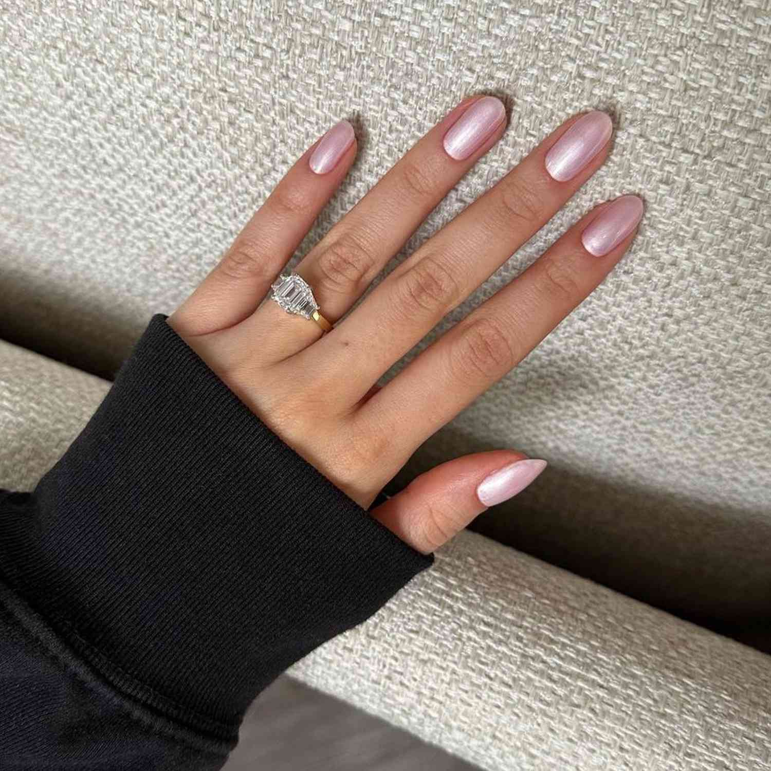 Mão com manicure cromada rosa está em móveis