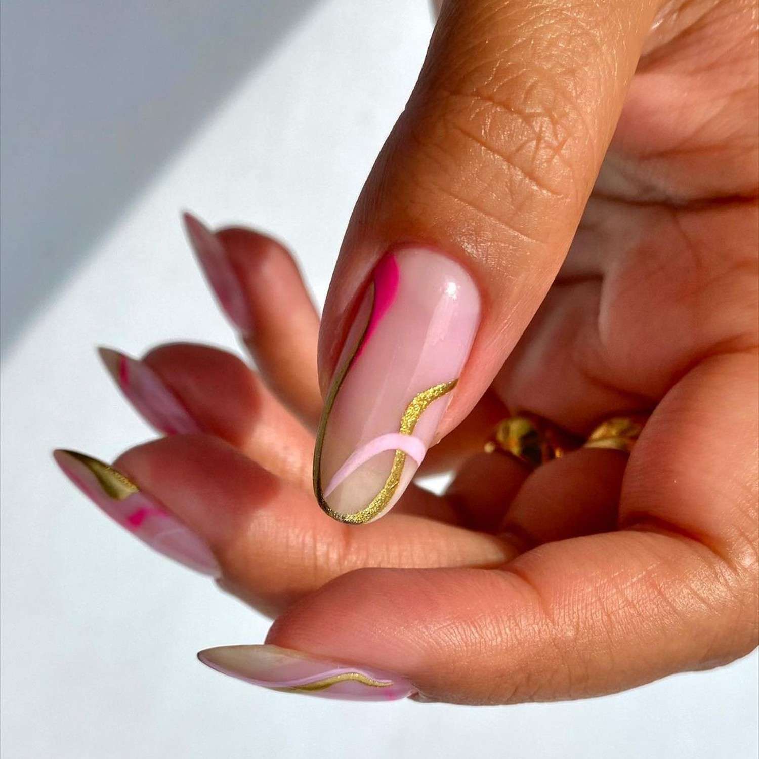 Manicure minimalista com cachos rosa e dourado