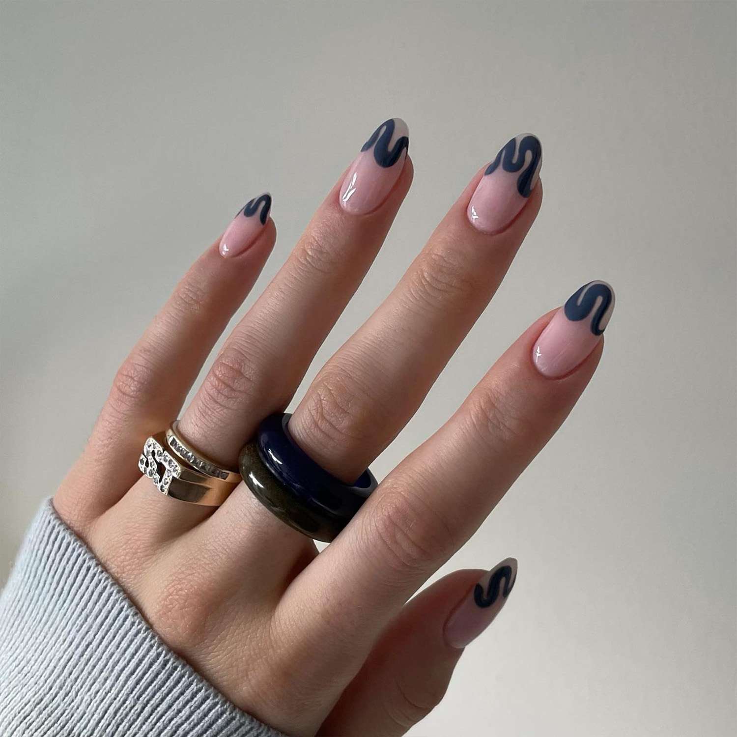 Close de uma manicure com um desenho de unhas de cor jeans escuro em forma de linha ondulada