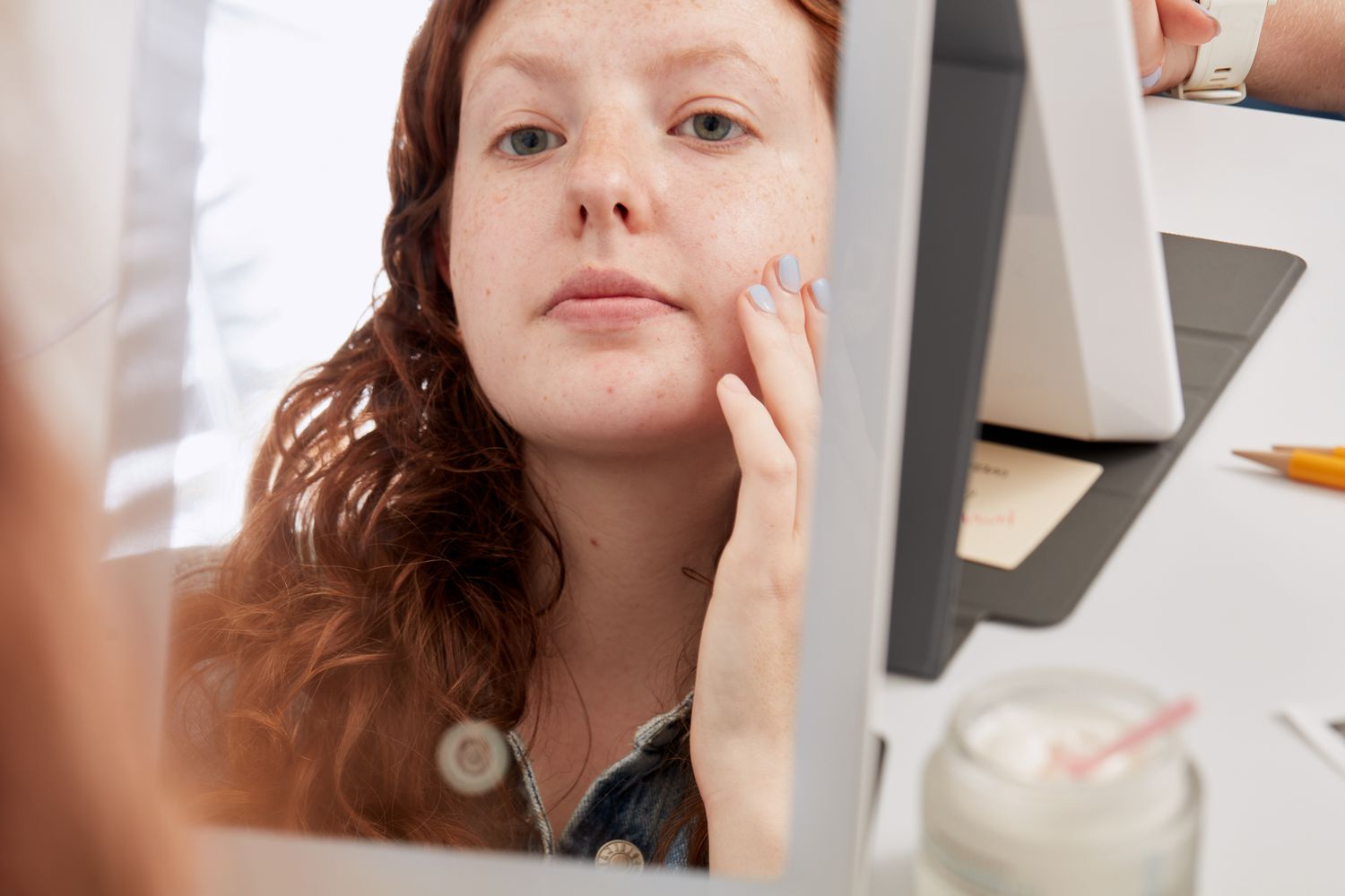 Uma pessoa que se aplica a SkinCceuticals Triple Lipid Restore 2: 4: 2 em seu rosto, no espelho