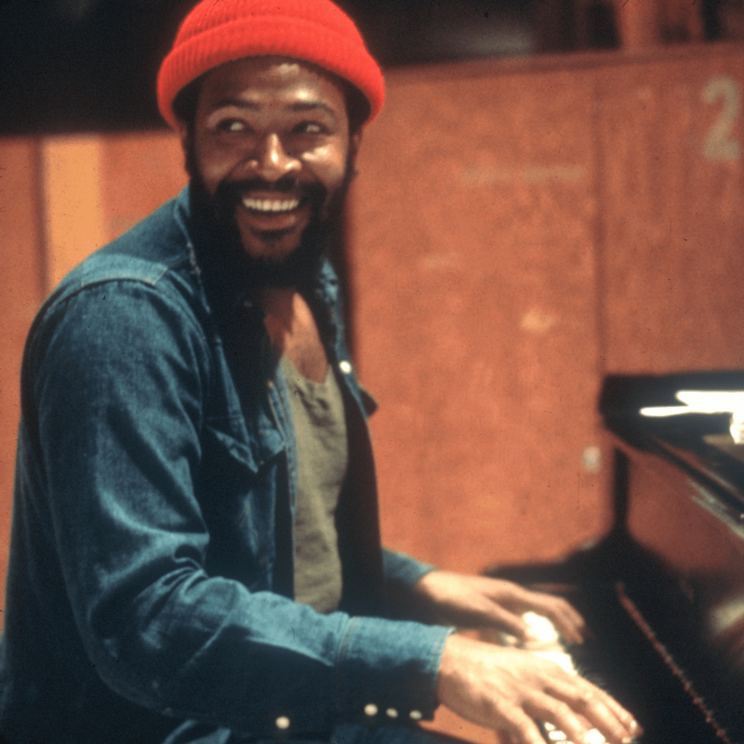 Marvin Gaye de chapéu vermelho sentado ao piano