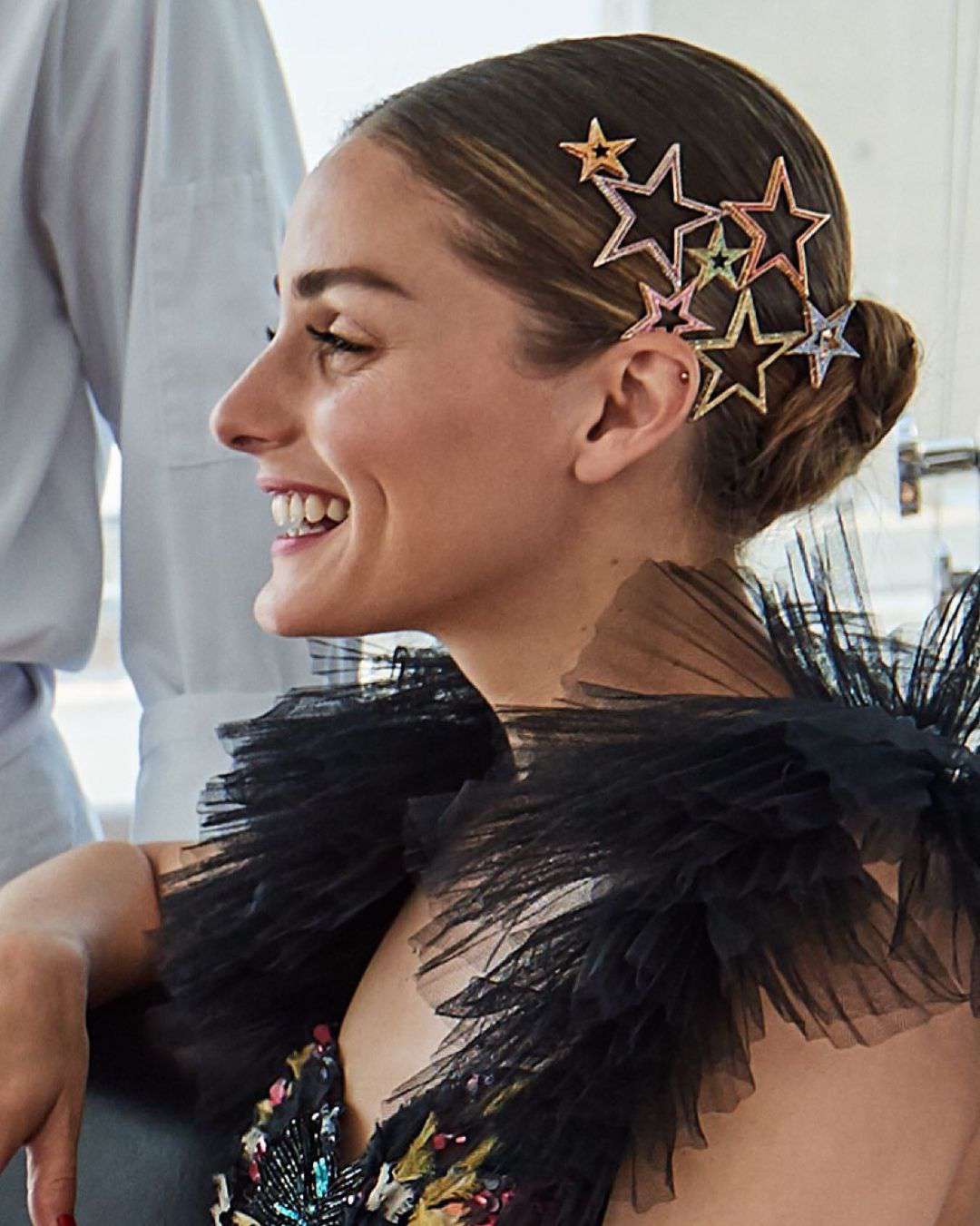 Olivia Palermo usa um coque baixo com clipes coloridos de estrelas