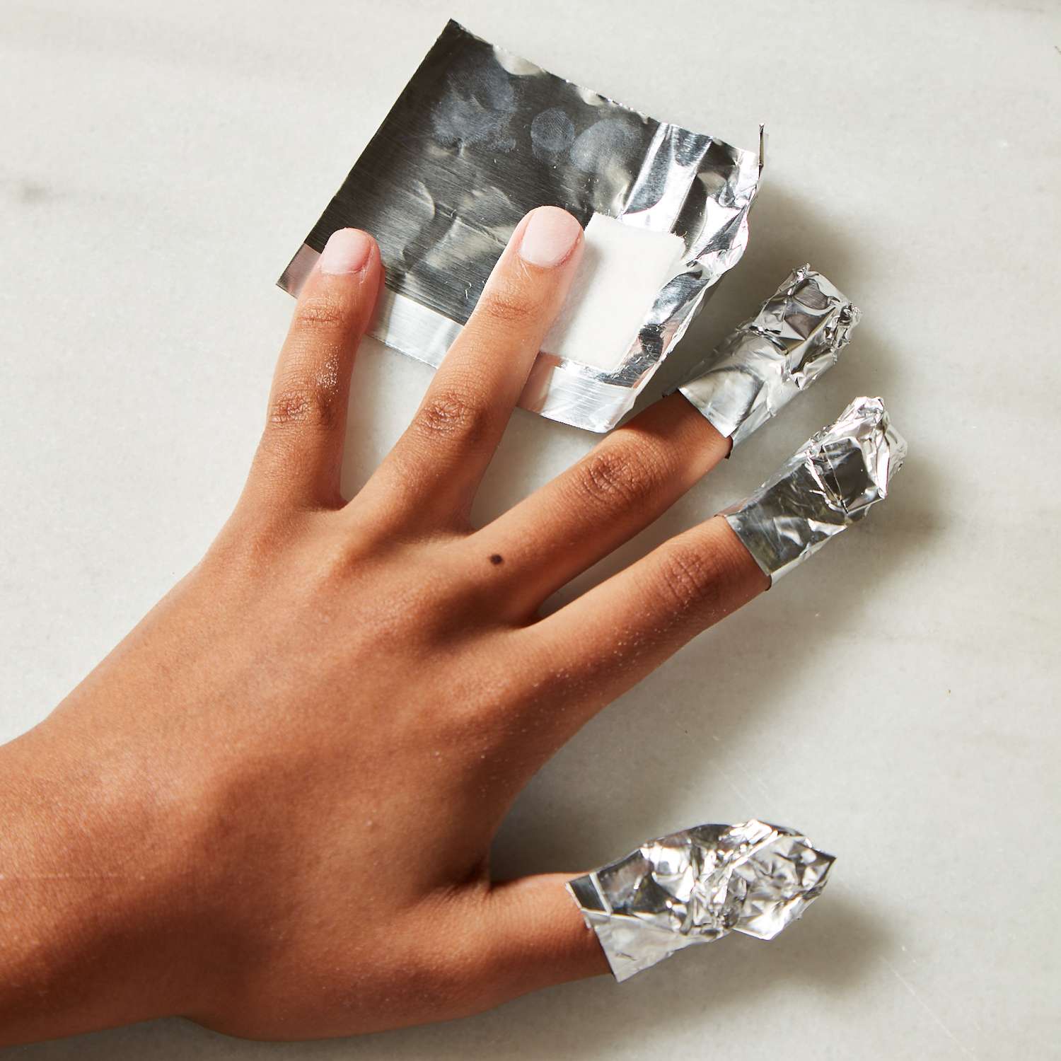 Mão de uma mulher com três dedos embrulhados em papel alumínio