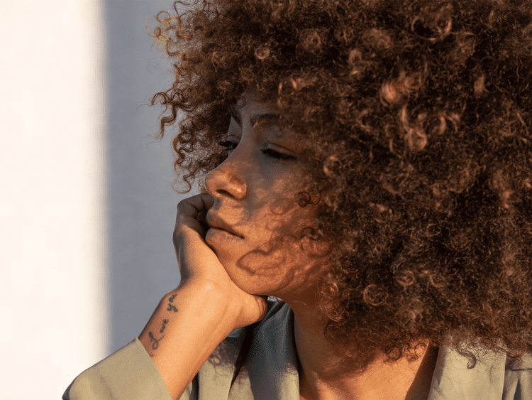 Retrato de uma mulher com afro e tatuagens