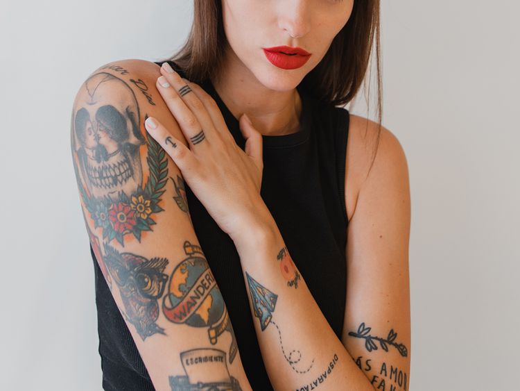Mulher tatuada com a mão no ombro